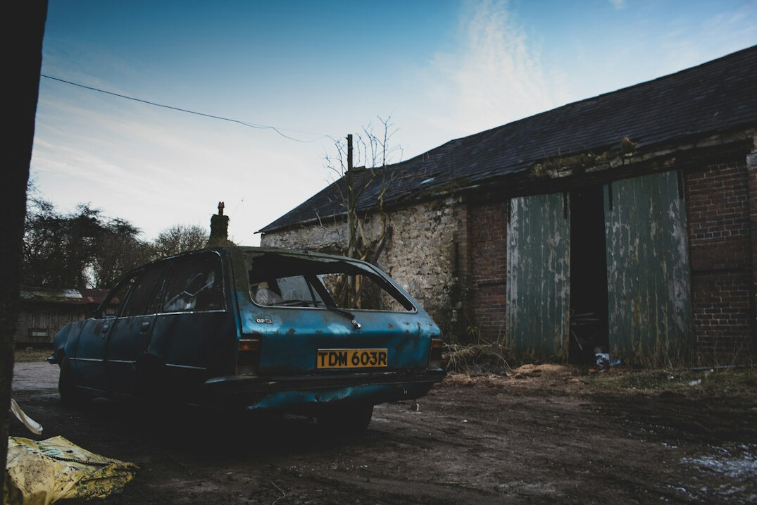 Forgotten classic car covered in a dust sheet inside an abandoned building